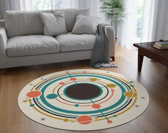 May include: A circular rug with a retro space design. It features teal, orange, and gold concentric circles, planet illustrations, and a dark brown centre. The rug is placed on a wooden floor.