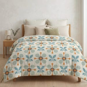 May include: A bed with a floral patterned comforter. The comforter features a repeating pattern of blue, orange, and green flowers on a cream background. The bed has several pillows in neutral colors.