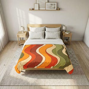 May include: A bed with a blanket featuring a retro wavy pattern in shades of orange, red, green, and cream. The blanket is spread over a bed with white pillows and a wooden headboard. The room has wooden floors and a neutral colour scheme.