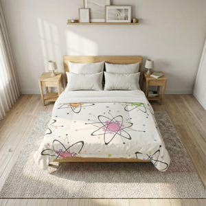 May include: A cream-colored comforter featuring a repeating pattern of atomic structures in black, pink, orange, and green, with colorful dot accents. The bedding is on a wooden bed frame with matching nightstands and lamps.