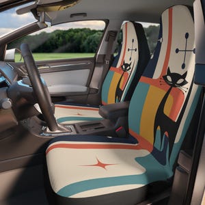 May include: Car seat covers with a retro design featuring a black cat silhouette and atomic starbursts. The covers have a cream background with stripes of orange, blue, and yellow. The cat has long whiskers and is set against a black background.