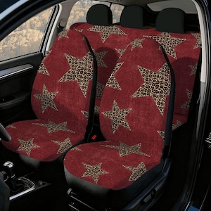 May include: A set of car seat covers featuring a deep red textured background with a repeating pattern of large five-pointed stars. Each star is filled with a brown and black leopard print design. The covers are fitted over the front and back seats.