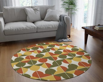 May include: A circular rug with a geometric design. The pattern consists of overlapping shapes in orange, yellow, and green against a cream backdrop. The rug is positioned on a wooden floor, creating a focal point in a living room.