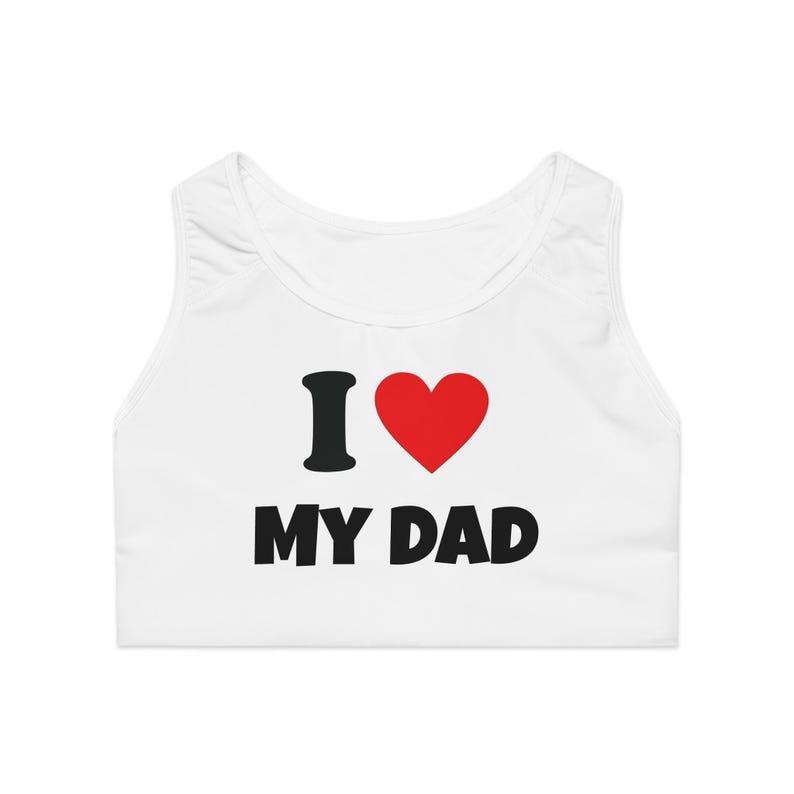 May include: White sports bra with the text "I &hearts; MY DAD" in black and a red heart. The bra is sleeveless and has a scoop neck. The text is centered on the front of the bra.