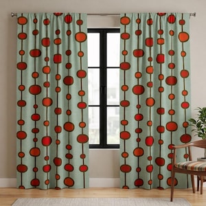 May include: Two light green curtain panels with a repeating pattern of red and orange ovals and rectangles connected by brown lines. The curtains hang in front of a black window frame. A wooden chair and a potted plant are visible.