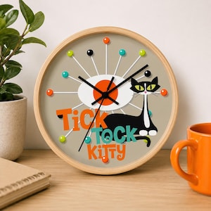 May include: A round wall clock with a light wood frame. The clock face is beige with a black cat illustration and the words "Tick Tock Kitty" in orange and teal. The clock has black hands and colorful dot markers.