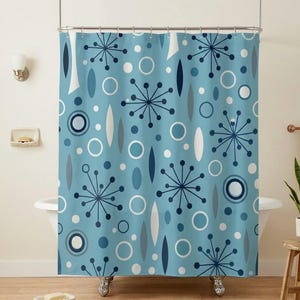 Könnte beinhalten: Hellblauer Duschvorhang mit einem Design der Moderne der Mitte des Jahrhunderts. Das Muster umfasst marineblaue Sternausbrüche, weiße und graue Ovale sowie Kreise unterschiedlicher Größe. Der Vorhang hängt in einem Badezimmer mit einer weißen Badewanne und Holzboden.