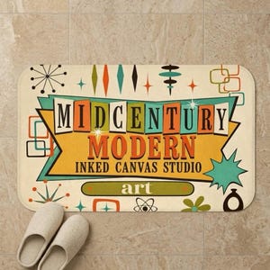 May include: Cream-coloured rectangular doormat featuring the words "MIDCENTURY MODERN INKED CANVAS STUDIO art" in a retro design. The mat has a colourful mid-century modern design with geometric shapes and a pair of white slippers.