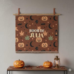May include: A brown Halloween tapestry with a repeating pattern of jack-o'-lanterns, bats, moons, stars, and leaves. The text "ROOM OF JULIA" is centered on the tapestry. The tapestry is hanging on a wooden rod with leather straps.