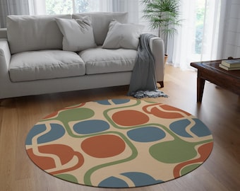 May include: A circular rug with a beige base and a retro design. It features large, rounded shapes in blue, green, and rust-orange, linked by curved lines. The rug is placed on a wooden floor, adding a pop of colour to the room.