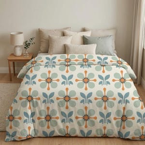 May include: A bed with a duvet cover featuring a repeating floral pattern in shades of light blue, orange, and green on a cream background. The bed is made with several pillows in neutral tones.