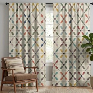 May include: Cream-colored window curtains with a repeating floral pattern in shades of red, blue, yellow, and purple. The curtains are hanging in front of a window, and a wooden chair with a striped pillow is in the foreground.