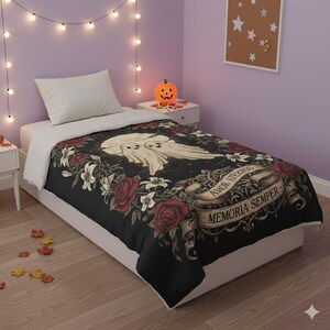 Può includere: Una trapunta nera con un design floreale e a forma di fantasma. La trapunta presenta rose rosse, gigli bianchi e uno stendardo con la scritta "AMOR AETERNUM MEMORIA SEMPER". La biancheria da letto è su un letto bianco.