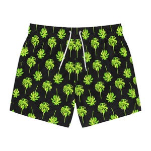 May include: Black swim trunks with a repeating pattern of bright green palm fronds. The trunks have a white drawstring and are made of a lightweight material. The shorts are designed for swimming and other water activities.