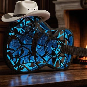 May include: Acoustic guitar with a black and blue design, topped with a white cowboy hat. The guitar features a detailed horse motif with a glowing blue interior. The instrument is set on a wooden surface, with a fireplace in the background.