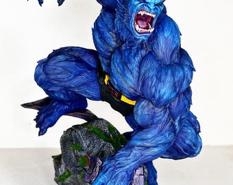 May include: A blue figurine of a muscular, beast-like character with sharp teeth and claws. The figure is posed dynamically, with a black belt and yellow buckle. It stands on a rocky base with green moss and purple accents.