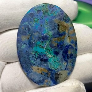 Peut inclure: Pierre d'azurite ovale polie. La pierre pr&eacute;sente un m&eacute;lange de bleus profonds, de turquoise et de nuances de brun. Les motifs naturels cr&eacute;ent un aspect marbr&eacute; unique. Id&eacute;ale pour la cr&eacute;ation de bijoux ou la collection. Mesures en centim&egrave;tres.