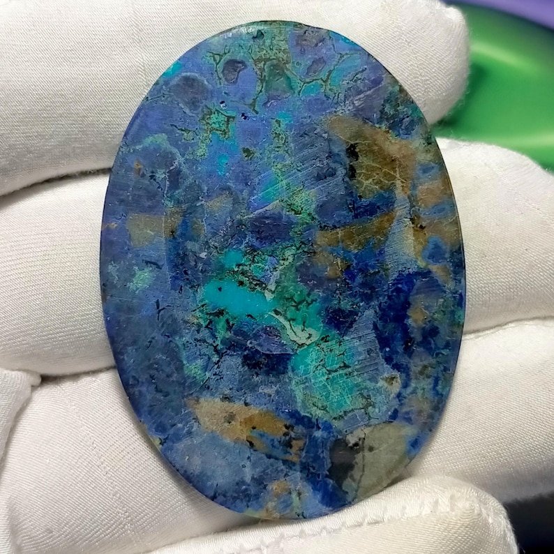 Peut inclure: Pierre d'azurite ovale polie. La pierre pr&eacute;sente un m&eacute;lange de bleus profonds, de turquoise et de nuances de brun. Les motifs naturels cr&eacute;ent un aspect marbr&eacute; unique. Id&eacute;ale pour la cr&eacute;ation de bijoux ou la collection. Mesures en centim&egrave;tres.