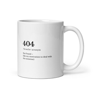 Könnte beinhalten: Weißer Keramikbecher mit gebogenem Henkel. Der Becher zeigt die schwarze Zahl "404" zusammen mit der Definition des Akronyms "Not Found" und dem Satz "(like my motivation to deal with this nonsense)".