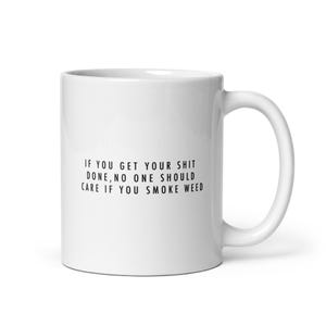 Puede incluir: Una taza de cerámica blanca con un asa curvada. La taza presenta el texto "IF YOU GET YOUR SHIT DONE, NO ONE SHOULD CARE IF YOU SMOKE WEED" en negro, centrado en la parte delantera. La taza está diseñada para bebidas calientes.