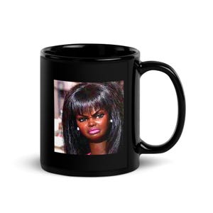 May include: Black ceramic mug featuring a printed image of a doll with a displeased expression, dark hair, and pink lipstick. The mug has a large handle for easy gripping and is suitable for hot or cold beverages.