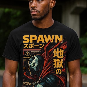 Könnte beinhalten: Schwarzes T-Shirt mit einer Grafik von Spawn, einer Comicfigur, mit japanischem Text und einem roten Umhang. Das Design enthält das Wort "SPAWN" in goldenen Buchstaben.