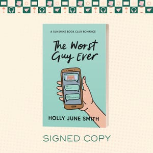 Op de afbeelding: Een boek getiteld "The Worst Guy Ever" met een lichtblauwe kaft. De kaft toont een smartphone met een tekstgesprek en een cartoonafbeelding. De naam van de auteur, Holly June Smith, staat onder de titel. De woorden "SIGNED COPY" staan onderaan.