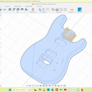 Peut inclure: Conception d'un corps de guitare bleu clair affichée sur un écran d'ordinateur. L'image est un dessin technique ou un plan, montrant les composants internes et la structure de l'instrument. L'interface du logiciel est visible.
