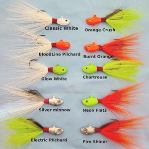 Könnte beinhalten: Eine Auswahl an Angelködern in verschiedenen Farben, darunter Weiß, Orange, Grün und Silber. Jeder Köder hat einen Haken und ist mit Namen wie "Classic White", "Orange Crush" und "Fire Shiner" versehen.