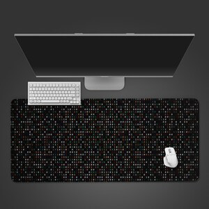 May include: A black rectangular mouse mat featuring a binary code design in green, orange, and brown. A white keyboard and mouse sit on the mat, with a computer monitor in the background.