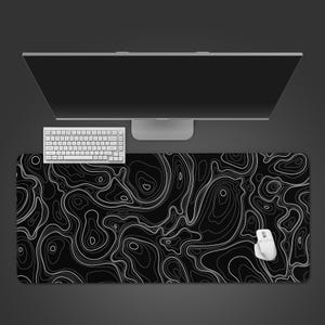 May include: A black and white topographic map design mouse pad with a white wireless mouse, keyboard, and computer monitor. The mouse pad features a detailed, abstract pattern of contour lines.