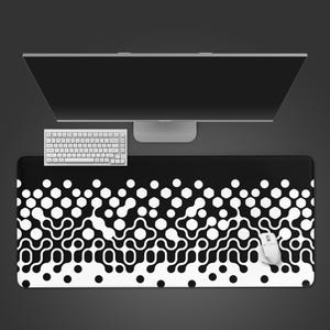 May include: A black and white patterned desk mat with a computer keyboard and mouse. The mat features a repeating design of white circles and organic shapes against a black background. A computer monitor is in the background.