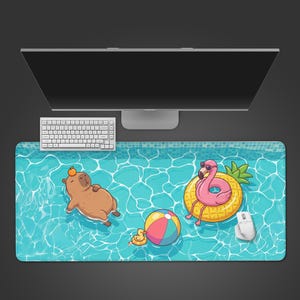 Op de afbeelding: Rechthoekige bureaumat met een cartoon zwembadscène. Een capibara drijft op zijn rug, een flamingo met zonnebril op een ananasvlotter, een strandbal en een badeend. Witte toetsenbord en muis zijn ook zichtbaar. Afmetingen in centimeters.
