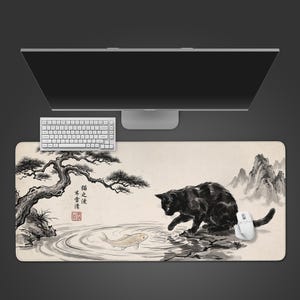 May include: A rectangular mouse mat with an Asian-inspired design. It features a black cat reaching towards a fish in a pond, with a tree and mountains in the background. A white keyboard and mouse are also present.