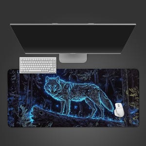 May include: A rectangular desk mat featuring a glowing blue wolf standing on a fallen log in a dark forest. The design includes intricate line work and a starry night sky background. A white computer keyboard and a white computer mouse are placed on top.