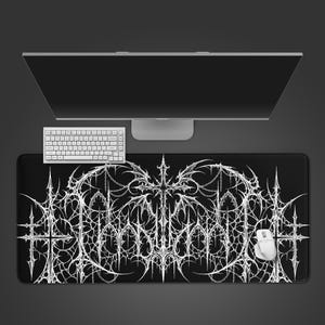 May include: Black rectangular mouse mat with a white gothic design, a white mouse, and a white keyboard. The design features a cross and chain elements. A computer monitor is in the background.