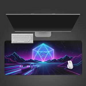 May include: A rectangular mouse mat with a retro-futuristic design. The mat features a neon-coloured landscape with a car, geometric shapes, and mountains. A white keyboard, mouse, and computer monitor are also visible.
