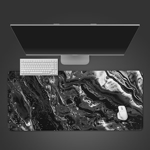 May include: A black and white marble-patterned desk mat with a white keyboard and mouse. The mat is rectangular and covers a large area of the desk. A computer monitor is visible in the background.