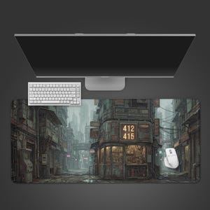 May include: A rectangular mouse mat with a detailed cityscape illustration in a futuristic, industrial style. The mat has a dark colour scheme with buildings, neon signs, and the numbers 412 and 415. A white keyboard, mouse, and monitor are on top.
