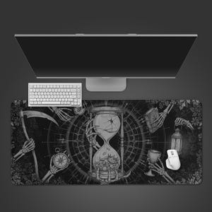 May include: A black and white desk mat with a gothic design. The mat features an hourglass, skeleton hands, a scythe, and a compass. A white keyboard and mouse are also present, with a computer monitor in the background.