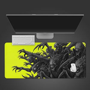 May include: A rectangular mousepad with a neon yellow background and a detailed black and gray illustration of menacing creatures. A white keyboard and mouse are visible. The mousepad is designed for computer use.