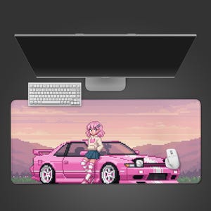 May include: A rectangular desk mat featuring a pixel art illustration of a character with pink hair leaning against a pink sports car. The background depicts a sunset landscape with mountains. A white computer keyboard and a white mouse are placed on the mat.