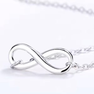 May include: A silver necklace featuring an infinity symbol pendant. The pendant is a polished, smooth design, connected to a delicate chain. The text "925 silver" is visible at the bottom of the image.