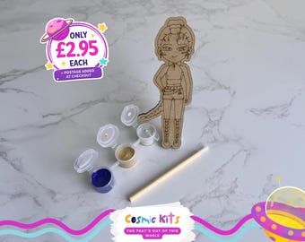 Puede incluir: Una figura de madera de un personaje de dibujos animados, botes de pintura y un palito de madera están dispuestos sobre una superficie de mármol. La figura es de color marrón claro con detalles grabados. Los botes de pintura contienen pintura azul, beige y blanca. El texto "Cosmic Kits" y "FUN THAT'S OUT OF THIS WORLD" son visibles.