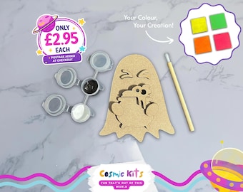Puede incluir: Un kit de manualidades con un recorte de madera en forma de fantasma, botes de pintura con pintura negra y blanca, un pincel y cuatro cuadrados de pintura de colores. El kit incluye el texto "Your Colour, Your Creation!" y "Cosmic Kits".