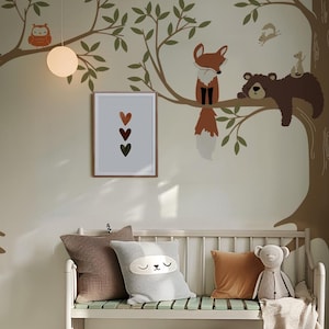 May include: A white bench with a light green slatted seat and a brown, gray, and white patterned pillow. A stuffed animal bear sits on the bench with a brown blanket. The wall behind the bench has a green tree mural with a fox, bear, owl, and squirrel.