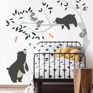 May include: A black and white nursery wall decal featuring a tree with a sleeping bear, two standing bears, and squirrels. The decal also includes a red owl and orange dragonflies.