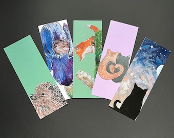 Op de afbeelding: Vijf rechthoekige boekenleggers met verschillende illustraties: een egel op groen, een blauwe iris, een vos en uil op groen, twee katten die een hart vormen op lavendel, en een silhouet van een zwarte kat tegen een sterrenhemel.