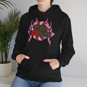 Könnte beinhalten: Schwarzer Kapuzenpullover mit einer Vordertasche. Die Grafik auf der Vorderseite zeigt die Worte "GIRL POWER" in einer verblassten Schriftart, mit einem roten Lippen-Design und rosa Flammen.