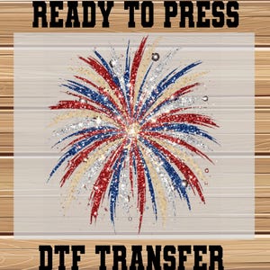 May include: A DTF transfer sheet featuring a central firework graphic with red, blue, silver, and gold glitter-style streaks radiating outward. The text READY TO PRESS is printed in black at the top, and DTF TRANSFER is printed in black at the bottom.